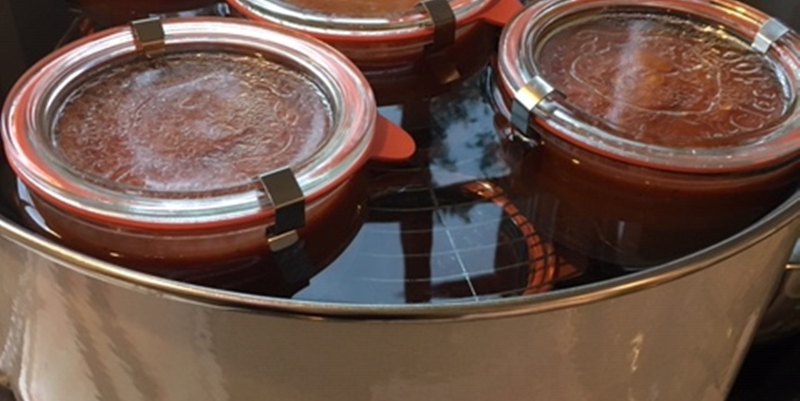 Abgefüllte Gläser mit Tomaten-Gemüsesauce im Wecktopf am einkochen 