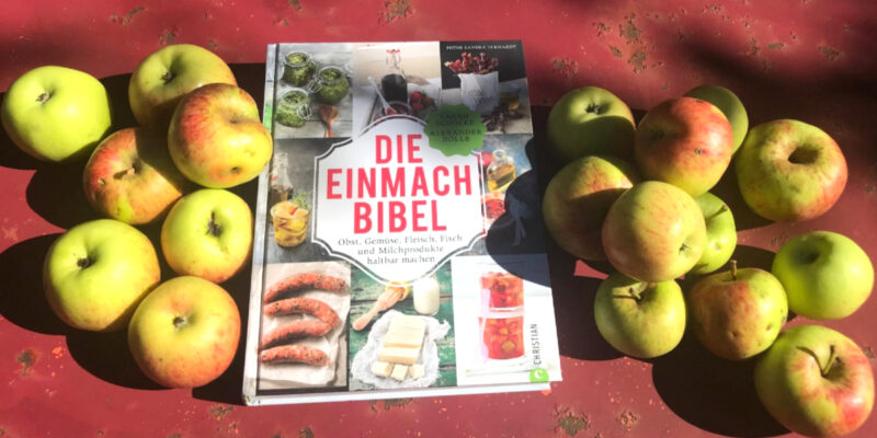Buch "Die Einmachbibel" mit Äpfeln auf rotem Blechtisch